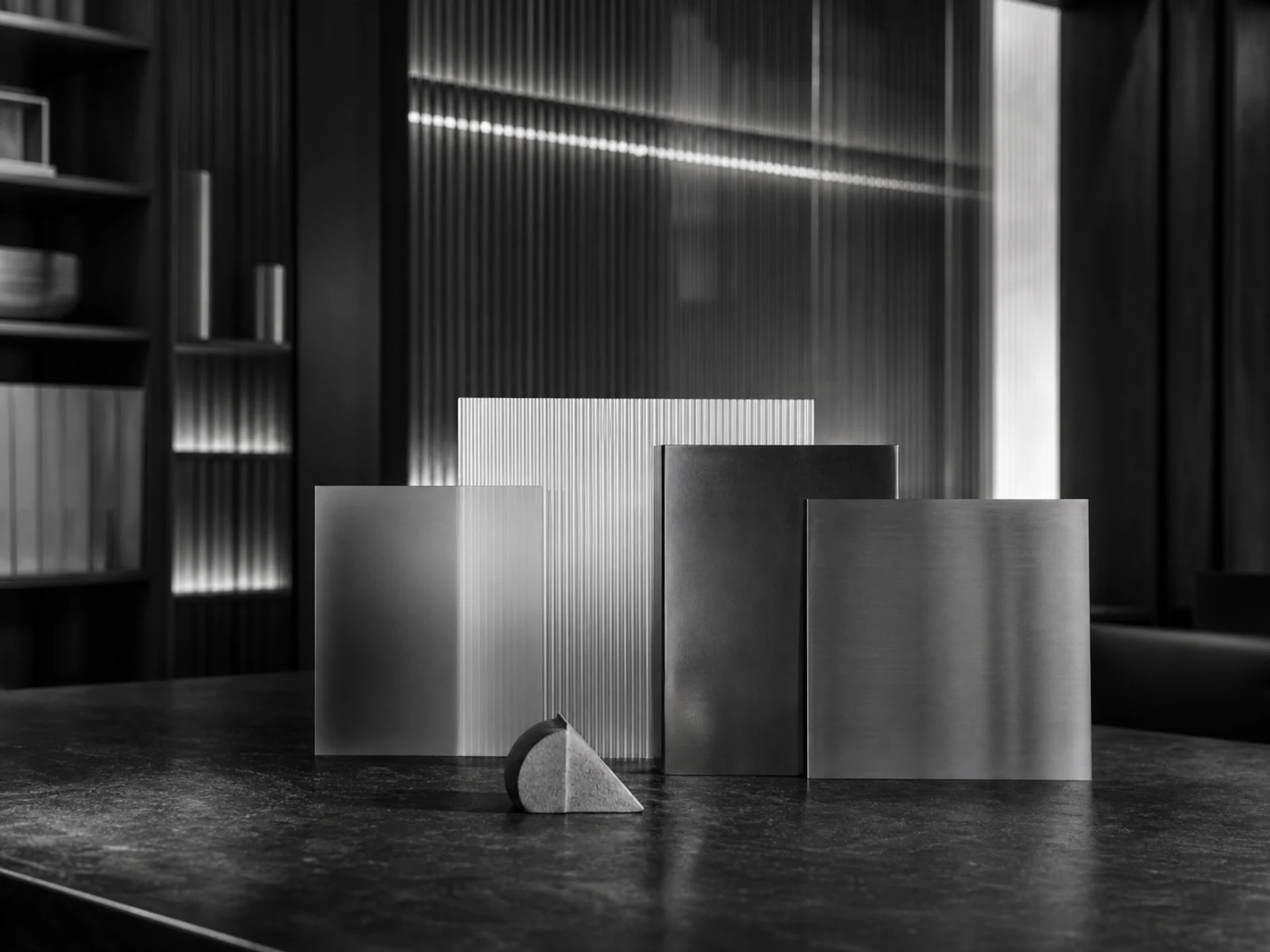 Composição editorial em preto e branco com placas geométricas alinhadas sobre mesa de pedra escura